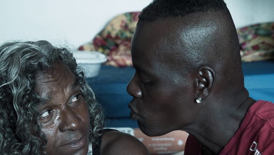 Imagem de duas pessoas negras num quarto em que uma tenta beijar a outra